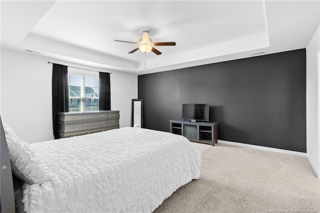 carpeted bedroom featuring a tray ceiling and ceiling fan