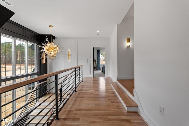 hall with wood-type flooring and a chandelier