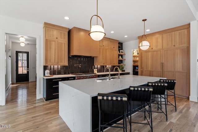 kitchen featuring tasteful backsplash, a large island, sink, and decorative light fixtures