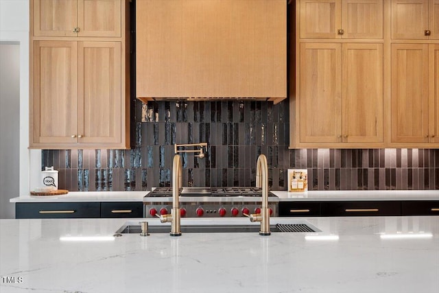 kitchen featuring light stone countertops, sink, decorative backsplash, and light brown cabinets