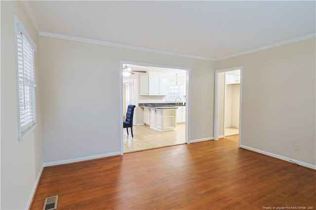 unfurnished room featuring crown molding, a wealth of natural light, and light wood-type flooring