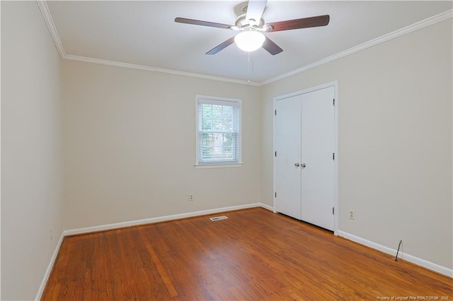 empty room with hardwood / wood-style floors, ornamental molding, and ceiling fan