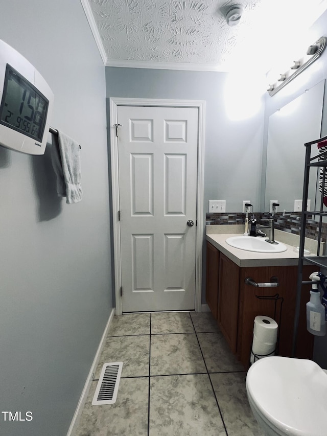 bathroom featuring tile patterned flooring, vanity, ornamental molding, toilet, and a textured ceiling