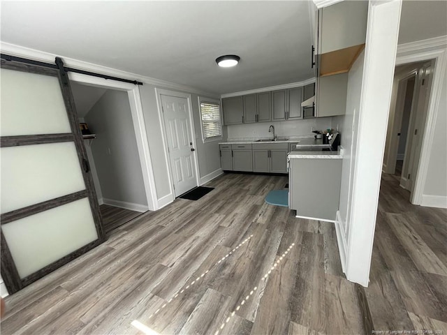 kitchen featuring sink, gray cabinets, dark hardwood / wood-style floors, ornamental molding, and a barn door