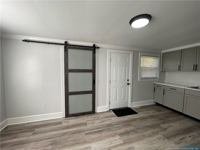 kitchen with gray cabinets, a barn door, and light wood-type flooring