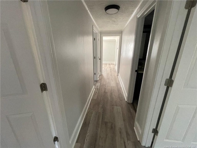 hall featuring dark wood-type flooring, crown molding, and a textured ceiling