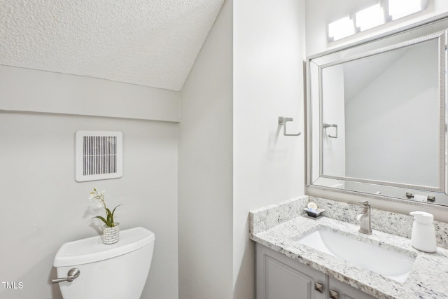 bathroom featuring vanity, toilet, vaulted ceiling, and a textured ceiling