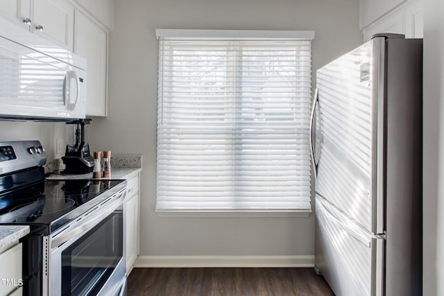 kitchen with white cabinetry, appliances with stainless steel finishes, dark wood-type flooring, and light stone counters