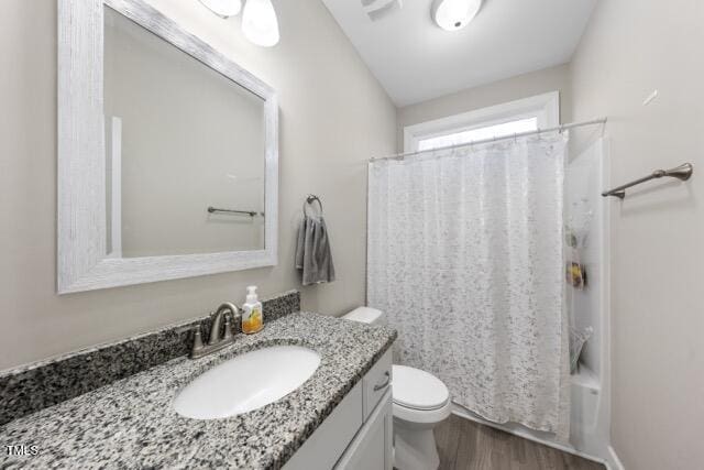 full bathroom with hardwood / wood-style flooring, shower / tub combo with curtain, vanity, and toilet