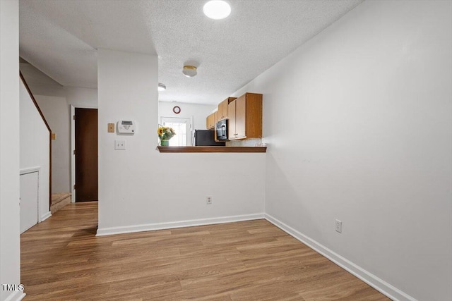 spare room with light hardwood / wood-style flooring and a textured ceiling