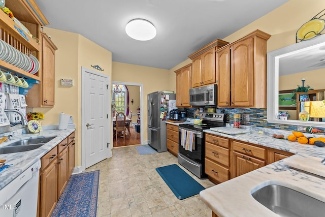 kitchen with brown cabinetry, decorative backsplash, appliances with stainless steel finishes, open shelves, and a sink