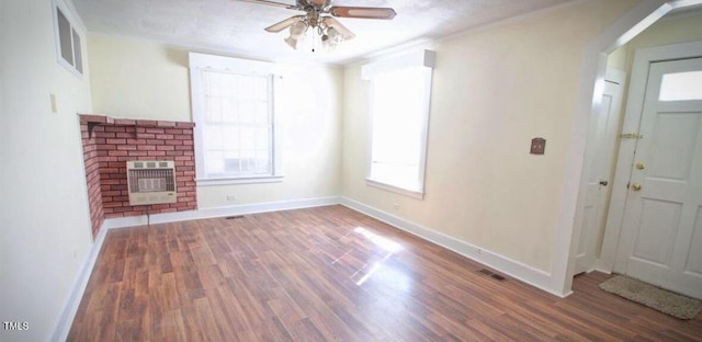 unfurnished living room with heating unit, crown molding, dark hardwood / wood-style flooring, ceiling fan, and a fireplace