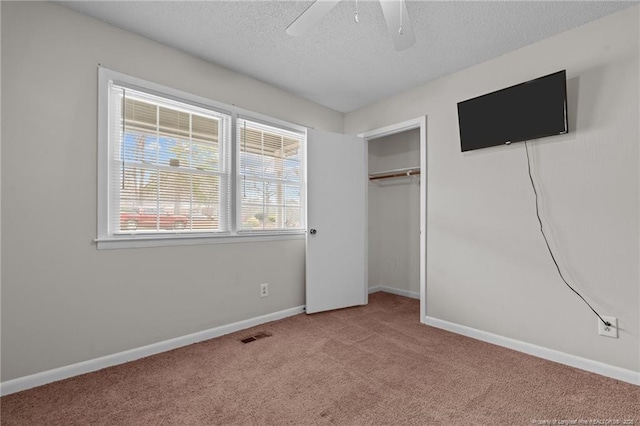 unfurnished bedroom with ceiling fan, light colored carpet, a closet, and a textured ceiling