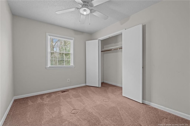 unfurnished bedroom with ceiling fan, light colored carpet, a closet, and a textured ceiling