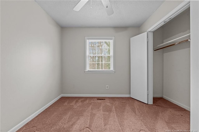 unfurnished bedroom with ceiling fan, carpet, a textured ceiling, and a closet