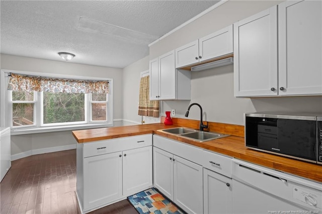 kitchen featuring sink, white cabinets, butcher block countertops, and kitchen peninsula