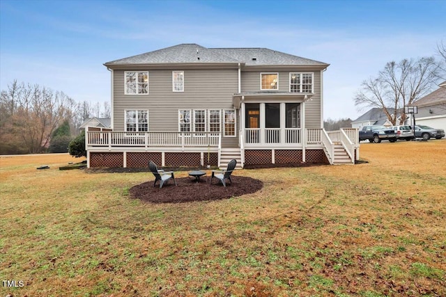 rear view of property featuring a wooden deck, a lawn, and a sunroom