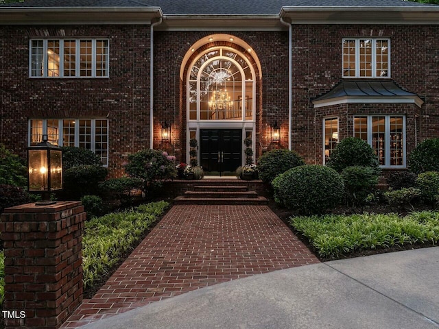 view of front of house featuring roof with shingles and brick siding