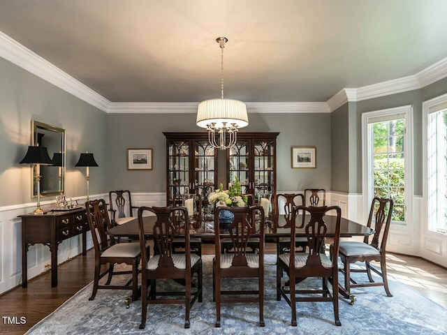 dining room featuring a chandelier, wainscoting, wood finished floors, and crown molding