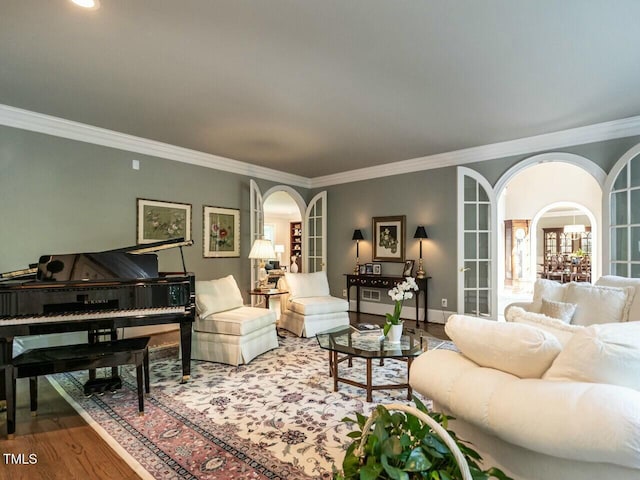 living area featuring ornamental molding, arched walkways, baseboards, and wood finished floors