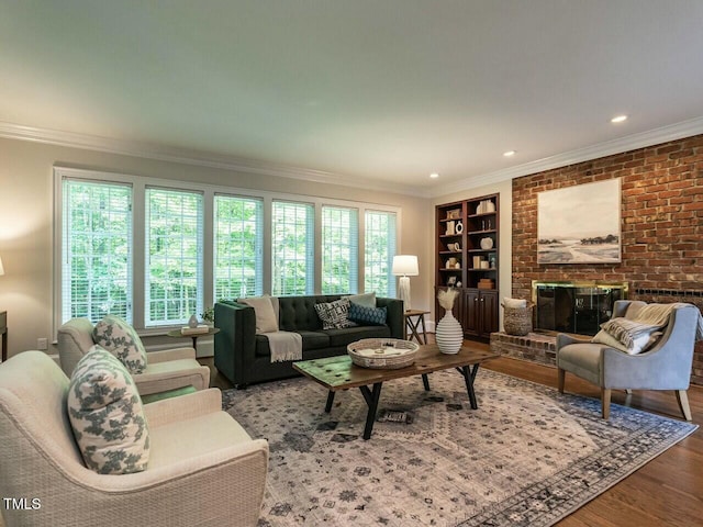 living area featuring ornamental molding, a brick fireplace, wood finished floors, and built in shelves