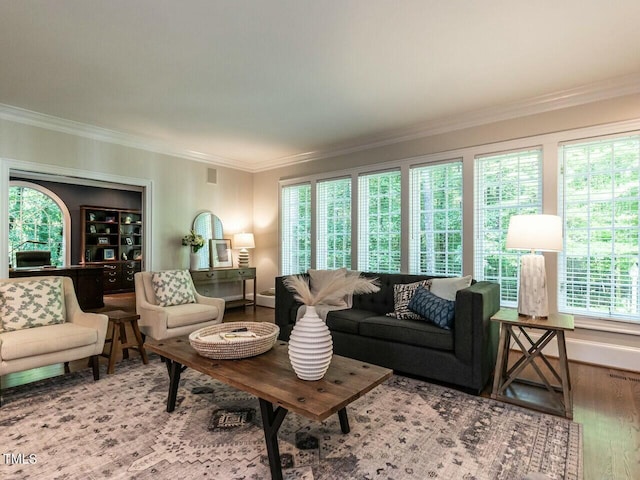 living area with baseboards, crown molding, visible vents, and wood finished floors