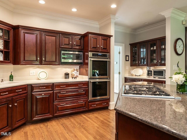 kitchen with light wood-style flooring, glass insert cabinets, appliances with stainless steel finishes, ornamental molding, and recessed lighting