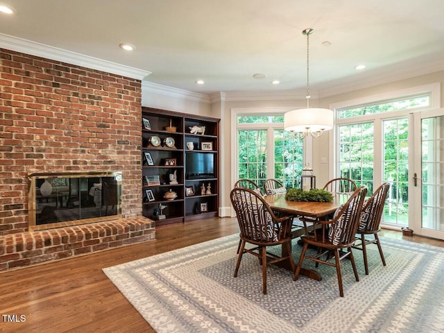 dining room featuring recessed lighting, a brick fireplace, crown molding, and wood finished floors