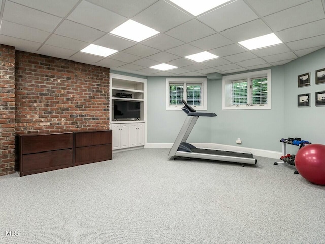 exercise room with carpet, a paneled ceiling, and baseboards