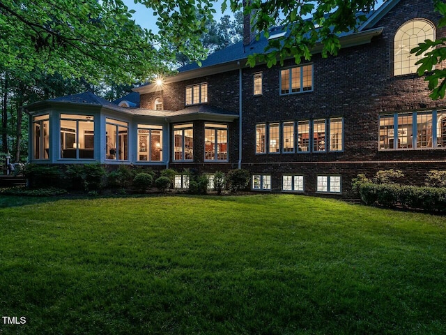 rear view of property with brick siding and a yard