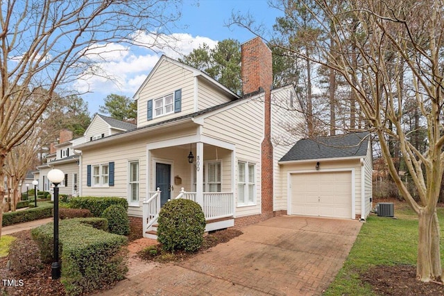 view of front facade with a porch, a garage, and central AC