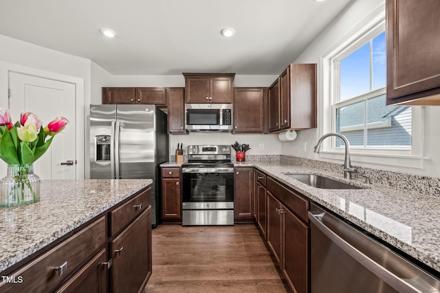 kitchen featuring appliances with stainless steel finishes, light stone counters, dark wood-style flooring, a sink, and recessed lighting