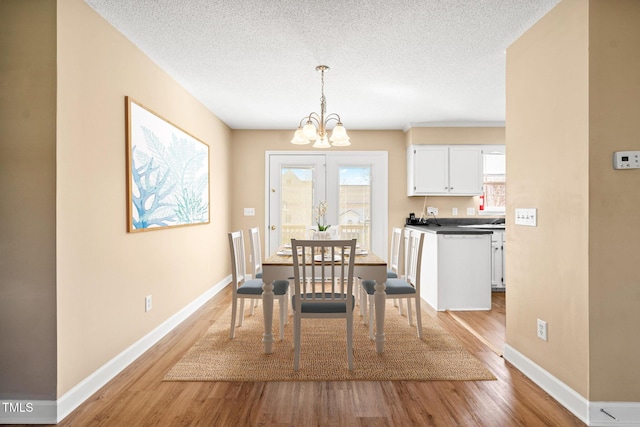 dining room featuring a notable chandelier, a textured ceiling, and light wood-type flooring