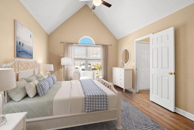 bedroom with ceiling fan, high vaulted ceiling, and hardwood / wood-style floors