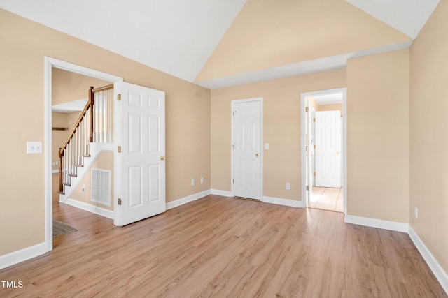 empty room with high vaulted ceiling and light wood-type flooring