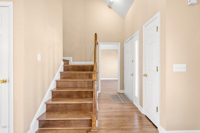 stairs featuring hardwood / wood-style flooring and vaulted ceiling