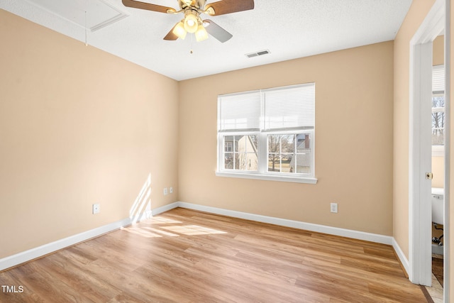 spare room with ceiling fan, a healthy amount of sunlight, a textured ceiling, and light hardwood / wood-style flooring