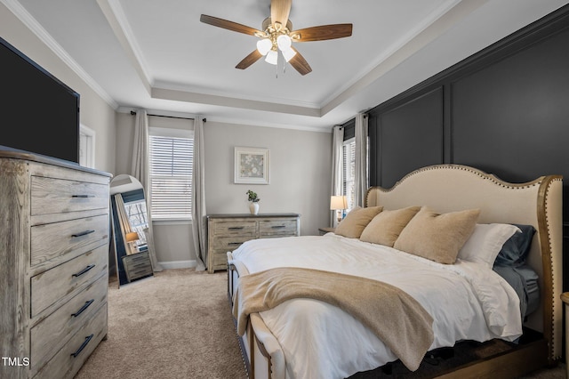 bedroom with a tray ceiling, crown molding, light colored carpet, a ceiling fan, and baseboards