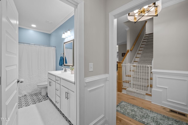 bathroom featuring toilet, a decorative wall, visible vents, vanity, and crown molding