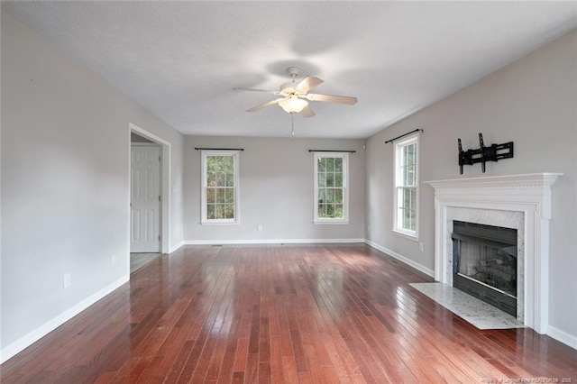 unfurnished living room with dark wood-type flooring, ceiling fan, and a fireplace