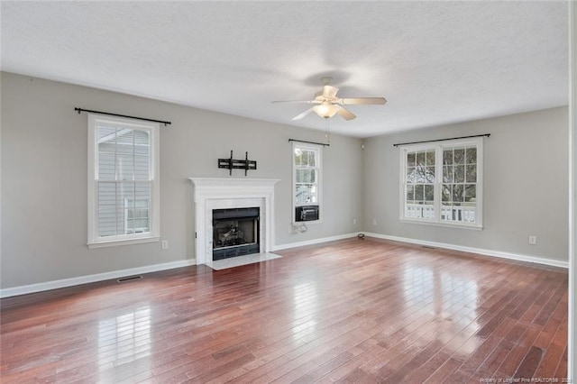 unfurnished living room with hardwood / wood-style floors, a textured ceiling, a high end fireplace, and ceiling fan