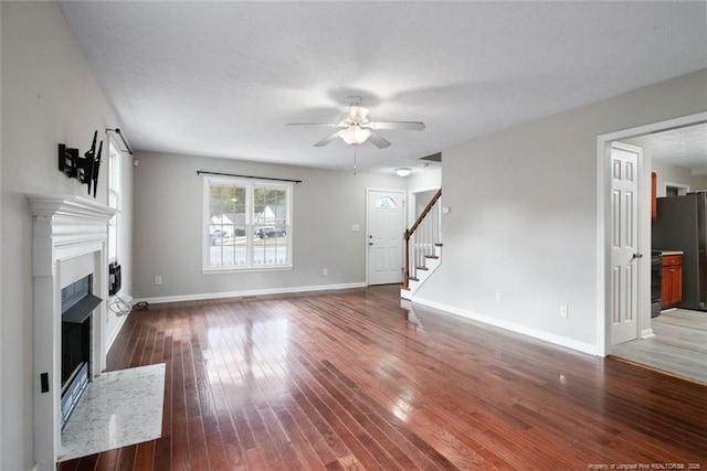 unfurnished living room featuring a textured ceiling, dark wood-type flooring, and ceiling fan