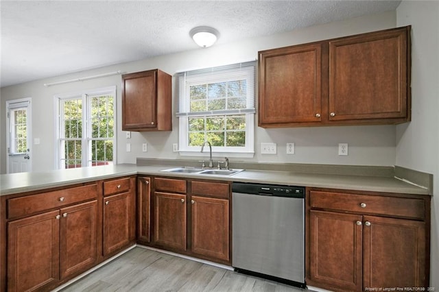 kitchen with sink, a textured ceiling, light wood-type flooring, dishwasher, and kitchen peninsula