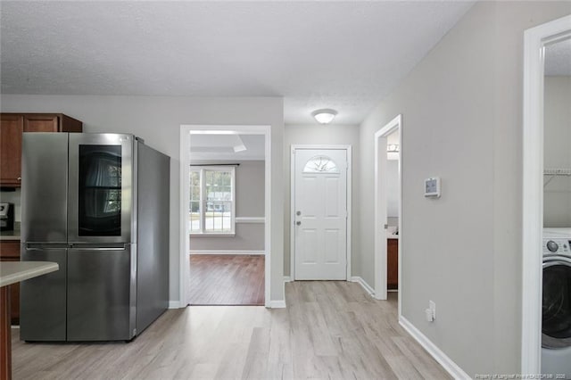 kitchen with washer / clothes dryer, a textured ceiling, stainless steel fridge, and light wood-type flooring