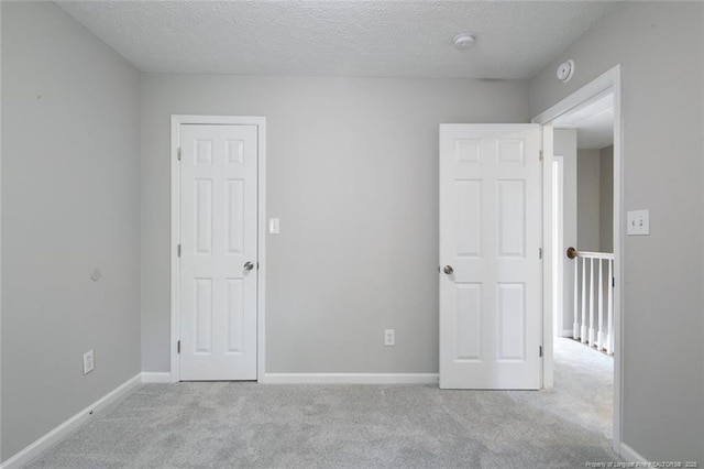 empty room featuring light colored carpet and a textured ceiling