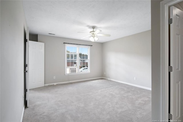 spare room featuring ceiling fan, light colored carpet, and a textured ceiling