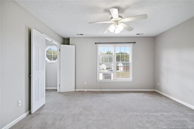 unfurnished bedroom with ceiling fan, light colored carpet, multiple windows, and a textured ceiling