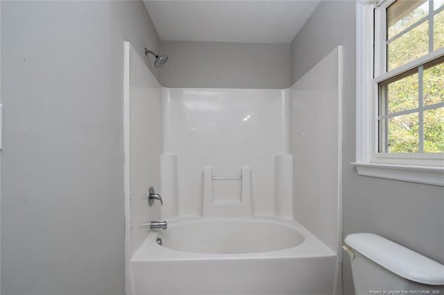 bathroom featuring tub / shower combination and toilet