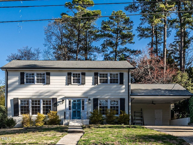 colonial home with driveway, a carport, and a front lawn