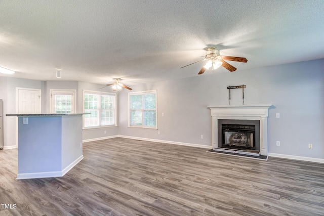 unfurnished living room with ceiling fan, a textured ceiling, and dark hardwood / wood-style flooring